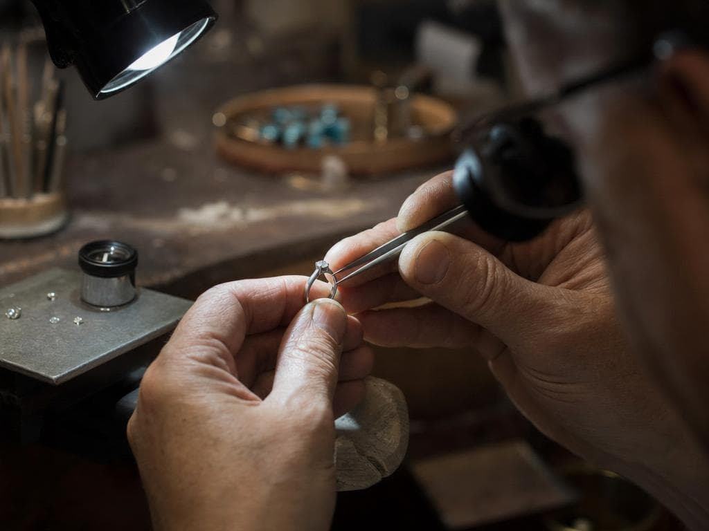 A jeweler setting a diamond into a finished ring under focused light